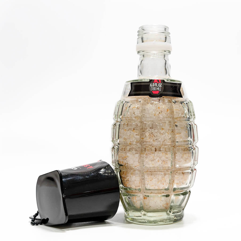 The Generals Hot Salt Clear glass bottle filled with coarse salt, with a black lid leaning against it on a white background.