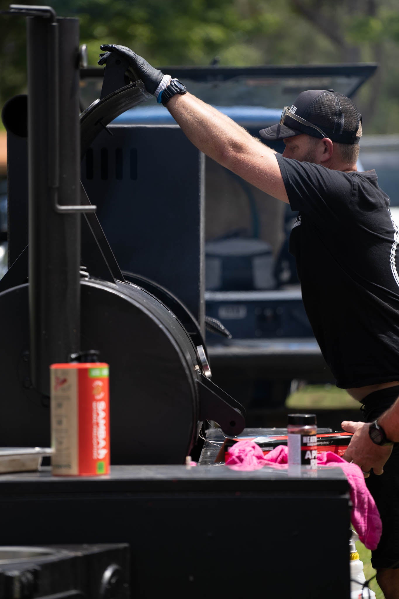 Paul from Red Smoke BBQ opening the door to the smoker, holding a tray of brisket at Smokiest GC BBQ Competition.